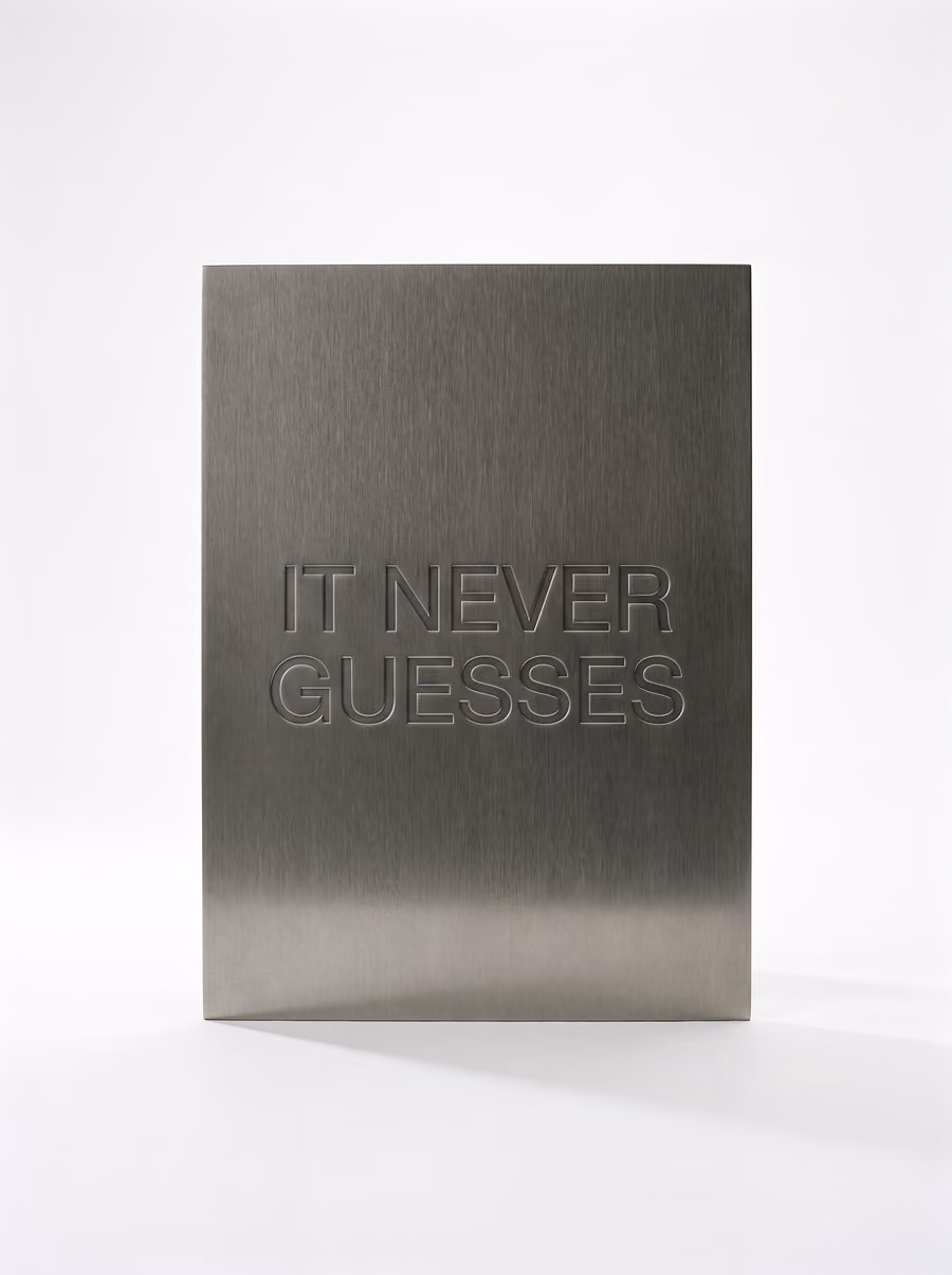 A brushed metal plate embossed with the words It never guesses.